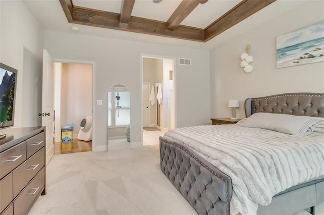 bedroom featuring beam ceiling, ensuite bathroom, light carpet, and ceiling fan