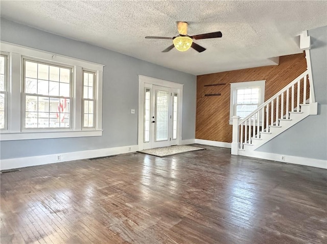 entrance foyer featuring ceiling fan, dark hardwood / wood-style flooring, wood walls, and a textured ceiling