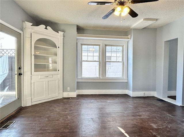 unfurnished dining area with ceiling fan, dark wood-type flooring, and a textured ceiling