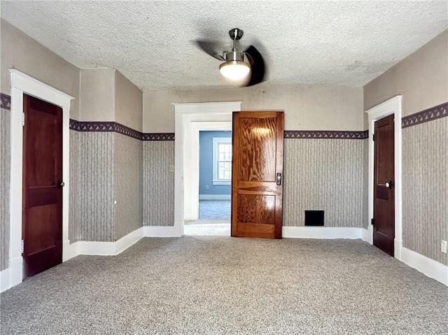 unfurnished bedroom with a textured ceiling, ceiling fan, and carpet floors