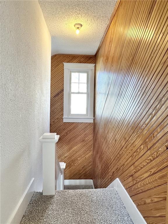 interior space with a textured ceiling and wooden walls