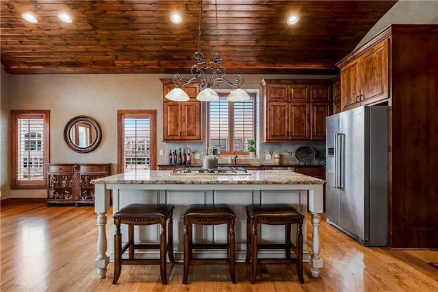 kitchen featuring hanging light fixtures, light stone countertops, a center island, and appliances with stainless steel finishes