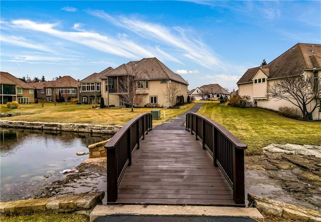 dock area with a water view, central air condition unit, and a lawn