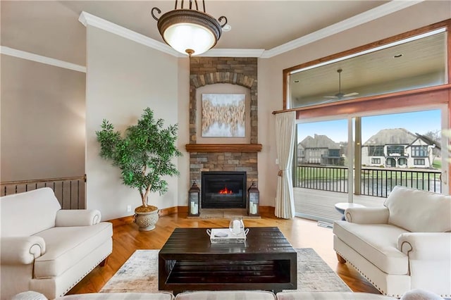 living room featuring ornamental molding, a stone fireplace, hardwood / wood-style floors, and ceiling fan