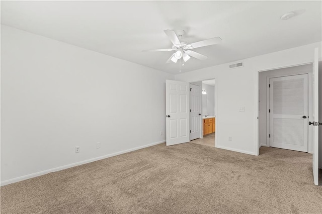 unfurnished bedroom with ceiling fan, light carpet, and ensuite bath