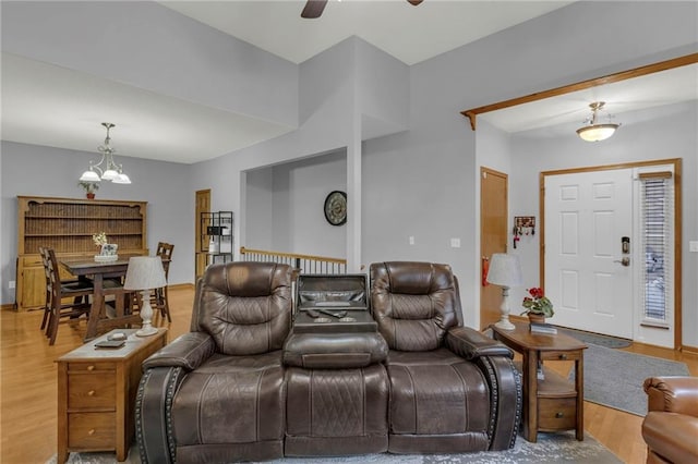 living room with ceiling fan with notable chandelier and hardwood / wood-style floors