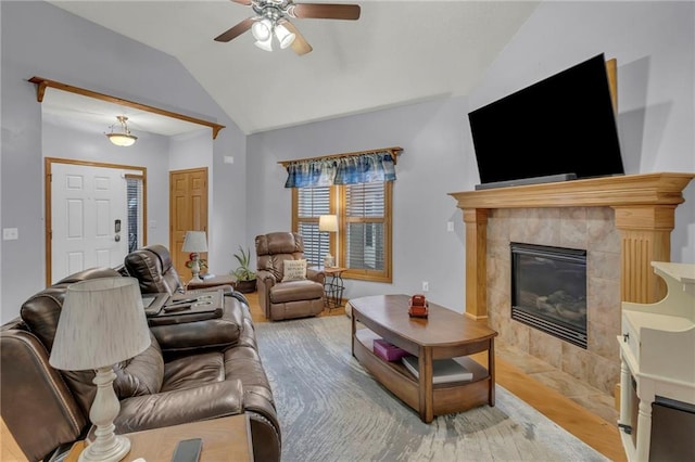 living room featuring hardwood / wood-style flooring, vaulted ceiling, ceiling fan, and a fireplace