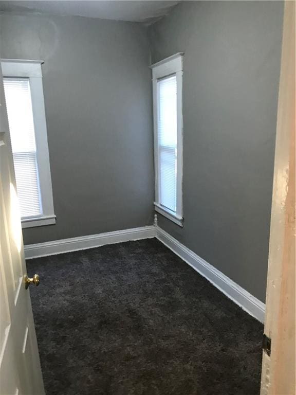 unfurnished room featuring dark colored carpet