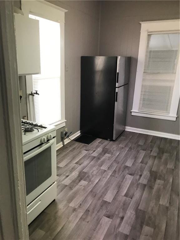 kitchen with stainless steel fridge, white gas range oven, and wood-type flooring