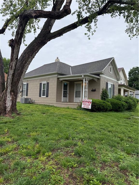2901 Messanie St, Saint Joseph, MO 64501 - view of front facade featuring a front yard, a chimney, roof with shingles, cooling unit, and covered porch