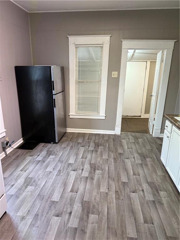 2901 Messanie St, Saint Joseph, MO 64501 - kitchen featuring freestanding refrigerator, light wood-style floors, white cabinets, dark countertops, and baseboards