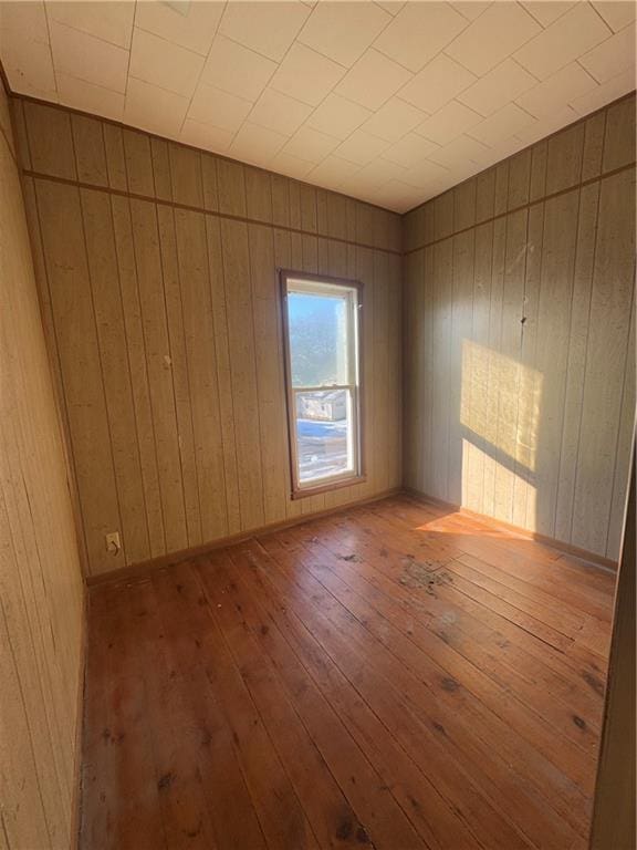 spare room with wood-type flooring and wooden walls