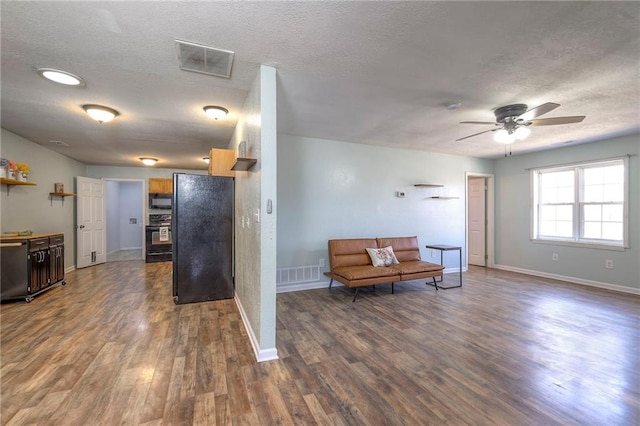 living area featuring a textured ceiling, dark wood finished floors, and visible vents