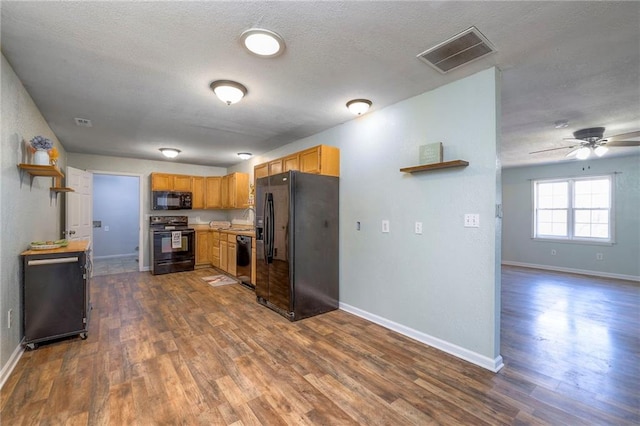 kitchen with black appliances, dark wood-style flooring, visible vents, and baseboards