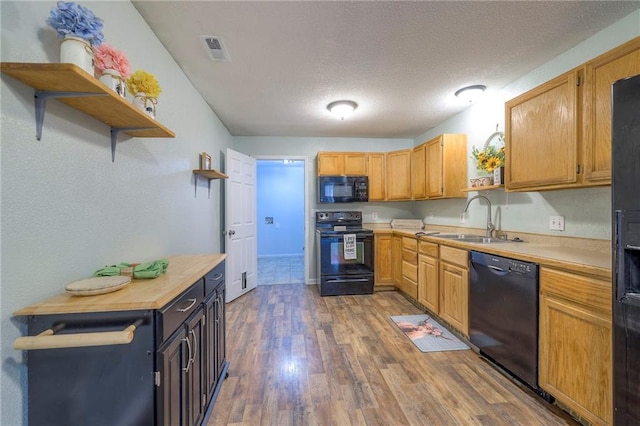 kitchen featuring open shelves, light countertops, visible vents, a sink, and black appliances