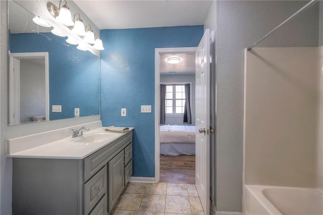 ensuite bathroom featuring a textured wall, vanity, ensuite bath, baseboards, and tile patterned floors