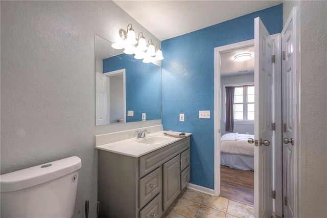 ensuite bathroom featuring a textured wall, toilet, ensuite bathroom, vanity, and tile patterned flooring