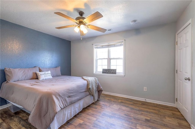 bedroom featuring ceiling fan, a textured ceiling, wood finished floors, visible vents, and baseboards