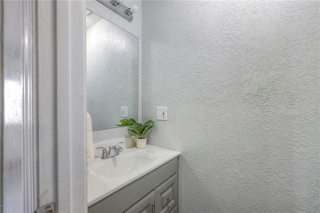 bathroom with a textured wall and vanity