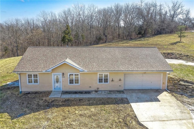 view of front of house with a garage, driveway, a front lawn, and a shingled roof