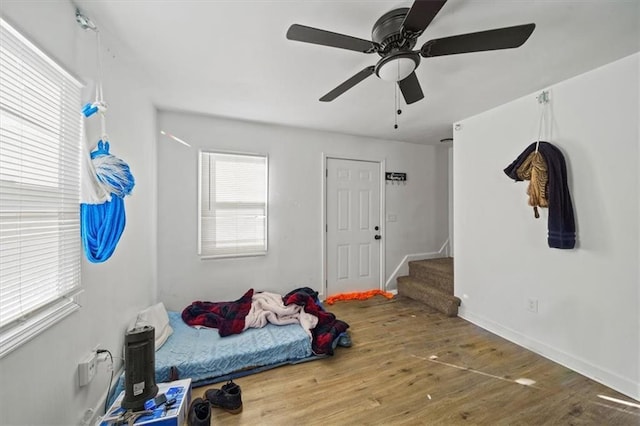 bedroom featuring a ceiling fan, baseboards, and wood finished floors