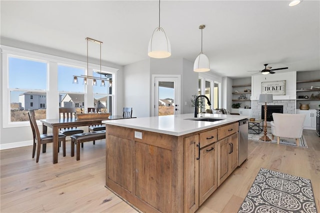 kitchen featuring decorative light fixtures, sink, a large fireplace, built in features, and a center island with sink