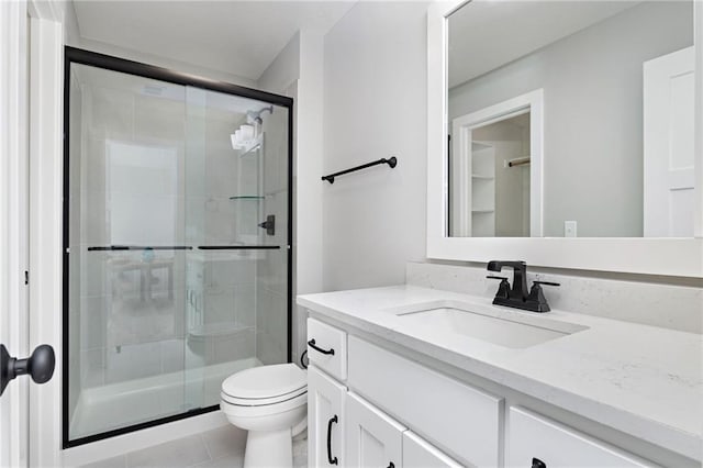 bathroom featuring toilet, tile patterned flooring, walk in shower, and vanity