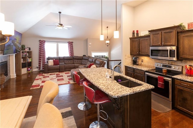 kitchen featuring decorative backsplash, sink, light stone countertops, appliances with stainless steel finishes, and a breakfast bar area