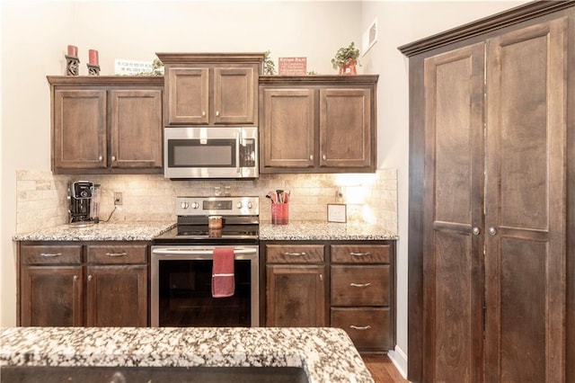 kitchen featuring appliances with stainless steel finishes, decorative backsplash, and light stone countertops