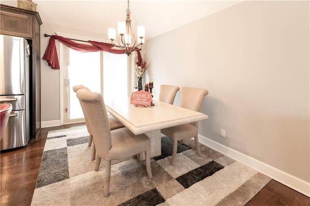 dining area with dark wood-type flooring, a wealth of natural light, and an inviting chandelier