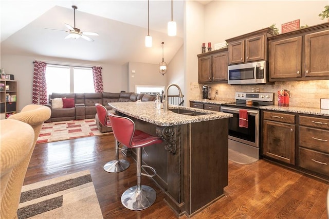 kitchen with a kitchen bar, stainless steel appliances, decorative backsplash, sink, and a kitchen island with sink