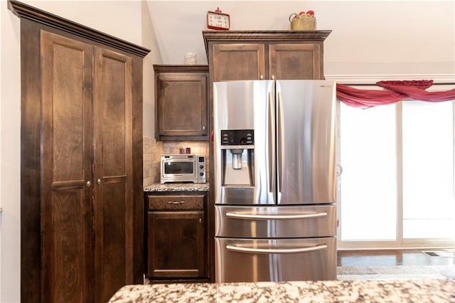 kitchen featuring tasteful backsplash, a healthy amount of sunlight, light stone countertops, and stainless steel fridge with ice dispenser