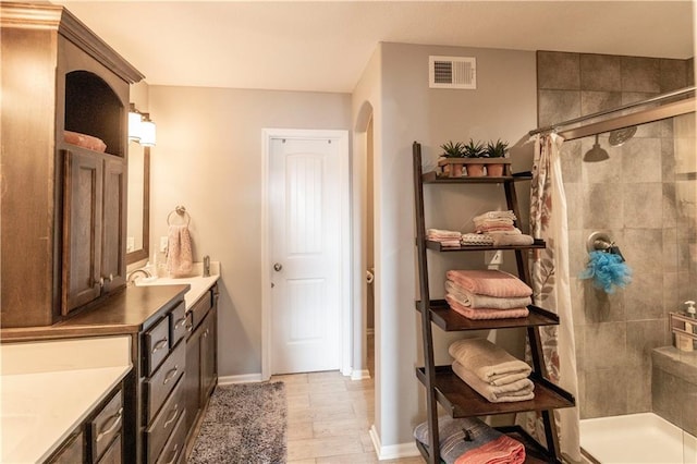 bathroom with hardwood / wood-style floors, vanity, and a tile shower