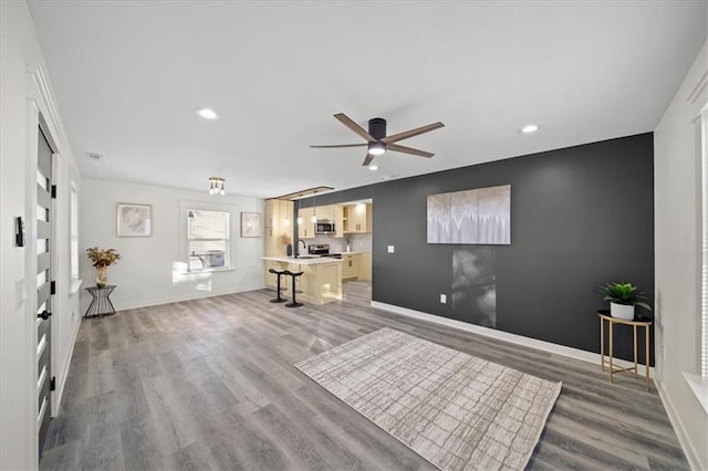 unfurnished living room with sink, hardwood / wood-style floors, and ceiling fan