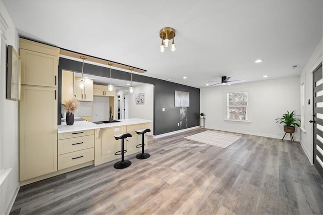 kitchen with sink, hardwood / wood-style floors, tasteful backsplash, a kitchen bar, and cream cabinetry