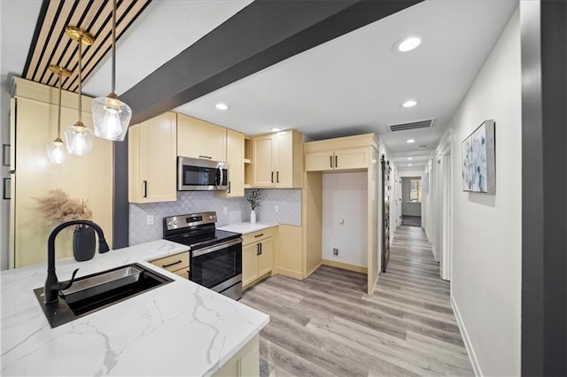 kitchen with sink, light stone counters, appliances with stainless steel finishes, pendant lighting, and backsplash