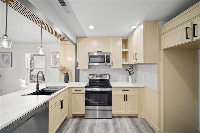 kitchen with pendant lighting, sink, stainless steel appliances, light hardwood / wood-style floors, and decorative backsplash