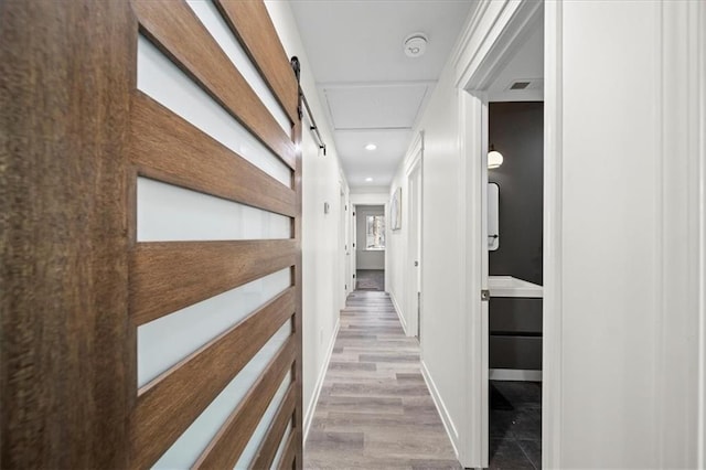 corridor featuring light hardwood / wood-style flooring and a barn door