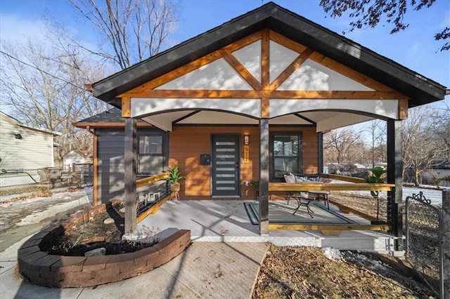 snow covered rear of property featuring covered porch