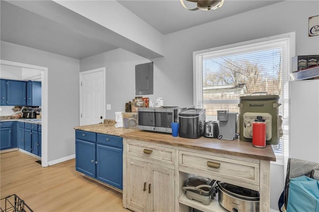 kitchen with a healthy amount of sunlight, light hardwood / wood-style flooring, blue cabinetry, and electric panel