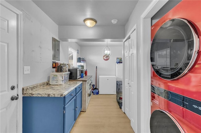 kitchen with fridge, stacked washer / drying machine, electric panel, and light wood-type flooring