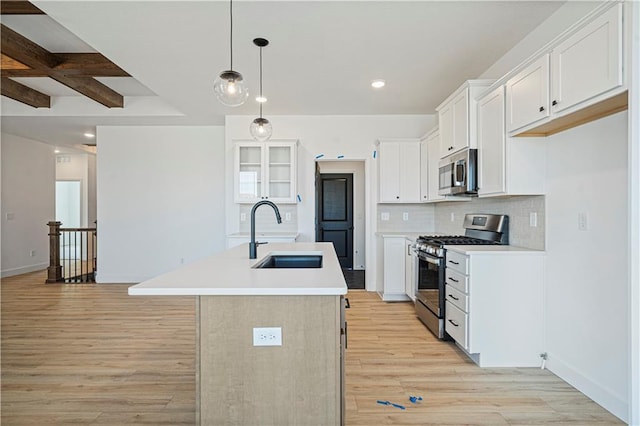 kitchen featuring white cabinets, stainless steel appliances, sink, a center island with sink, and beam ceiling