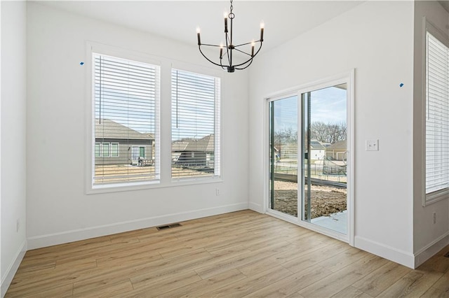 unfurnished dining area with light wood-type flooring and a notable chandelier