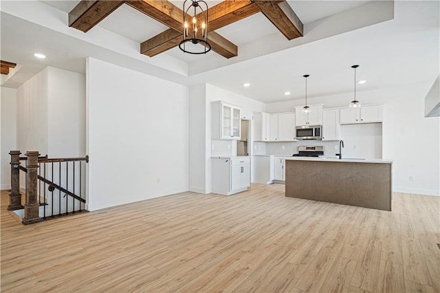 kitchen featuring a kitchen island, white cabinetry, appliances with stainless steel finishes, and decorative light fixtures