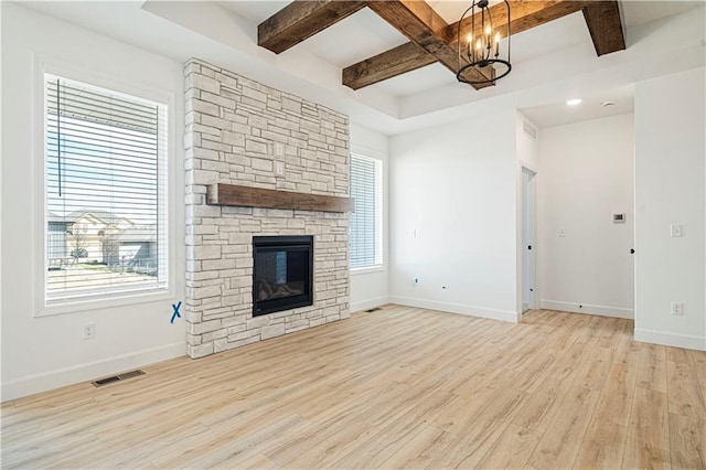 unfurnished living room with a stone fireplace, coffered ceiling, light wood-type flooring, beam ceiling, and an inviting chandelier