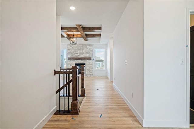 hallway featuring coffered ceiling, a notable chandelier, beamed ceiling, and light wood-type flooring