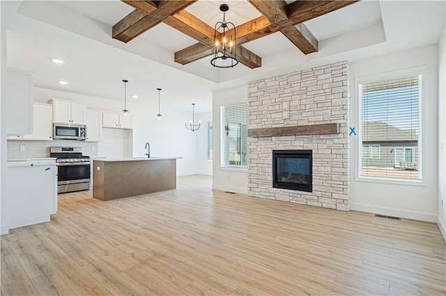 kitchen featuring stainless steel appliances, white cabinetry, a center island, and a notable chandelier