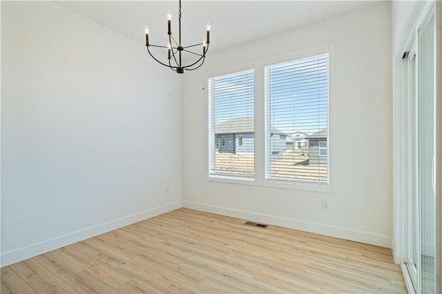 unfurnished dining area featuring an inviting chandelier and light hardwood / wood-style floors