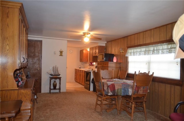 carpeted dining area featuring ceiling fan and wood walls