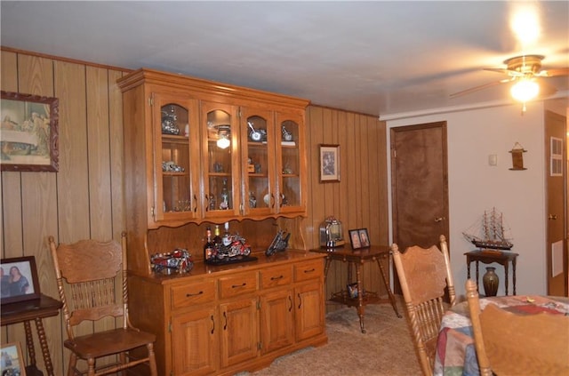 interior space featuring light carpet, ceiling fan, and wooden walls